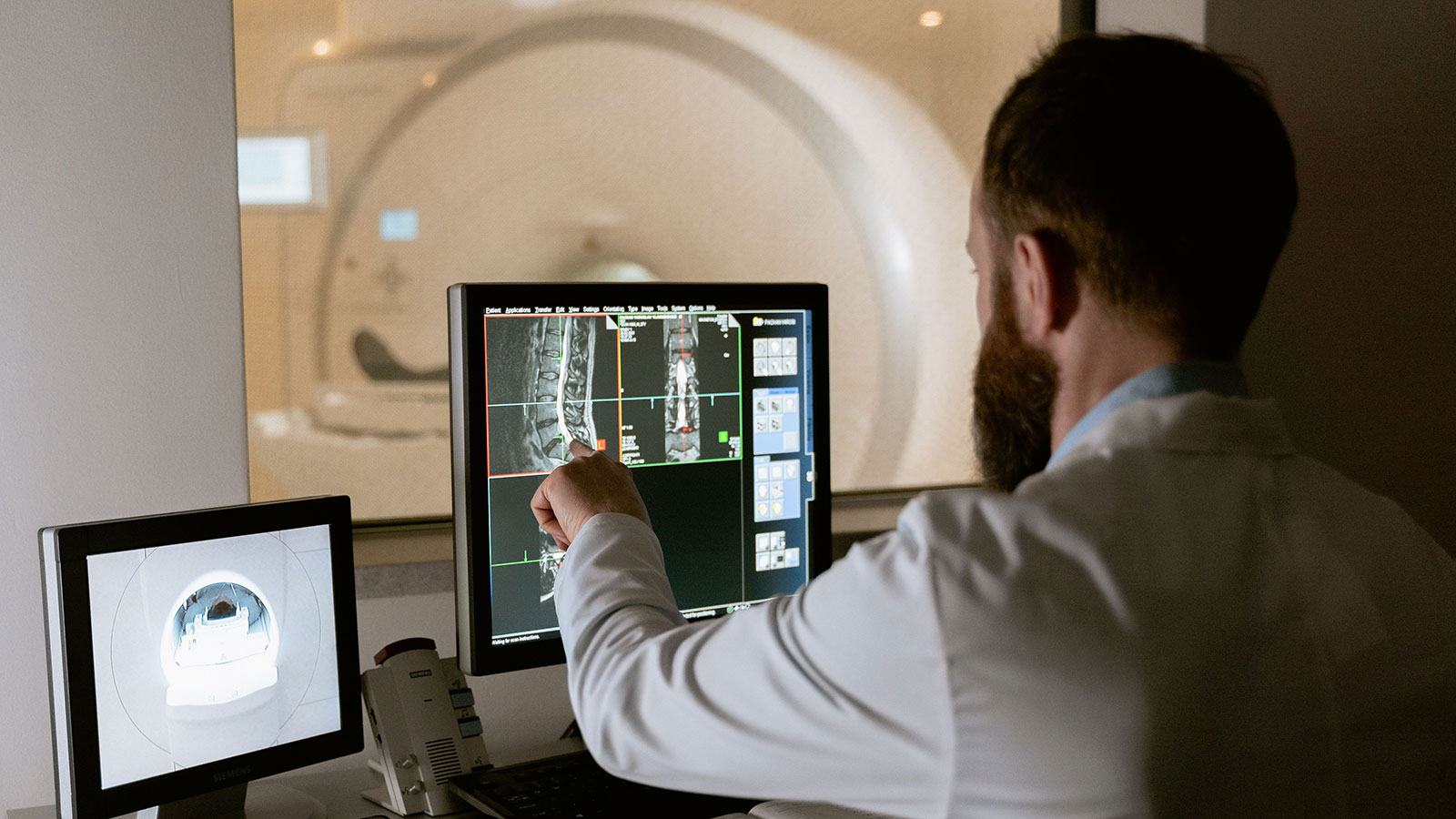 Medical professional reviewing MRI scans on computer screens for diagnostic purposes